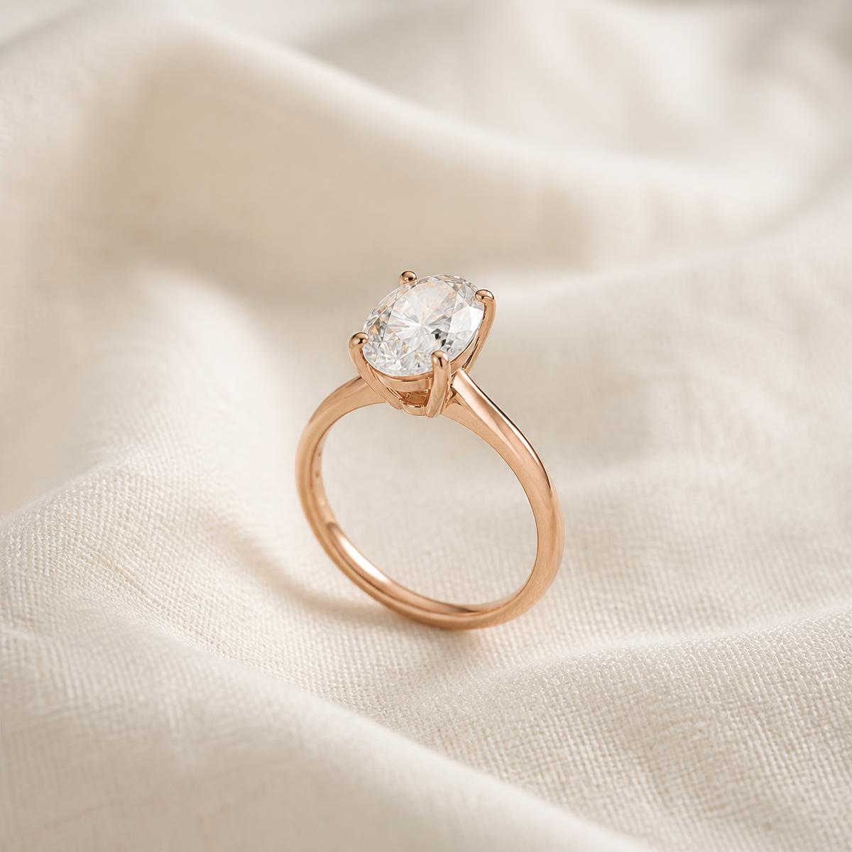 Oval moissanite ring with a rose-gold finish on ivory fabric