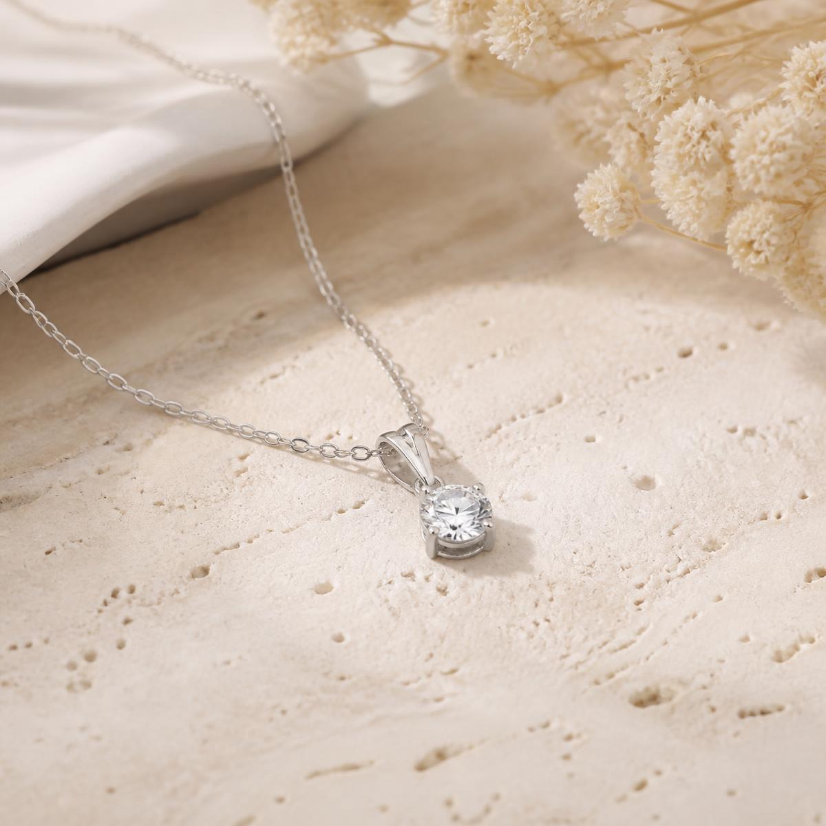 Solitaire moissanite pendant necklace with fine chain on warm stone
